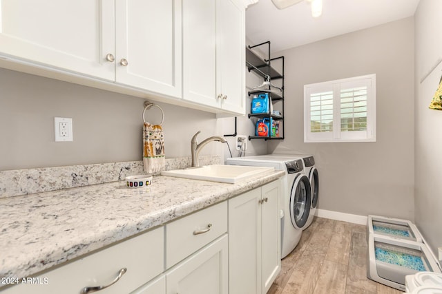 laundry area featuring cabinets, light wood-type flooring, washing machine and dryer, and sink