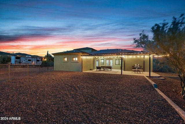 back house at dusk with an outdoor living space and a patio