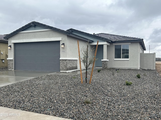 single story home featuring a garage, concrete driveway, a tiled roof, and stucco siding