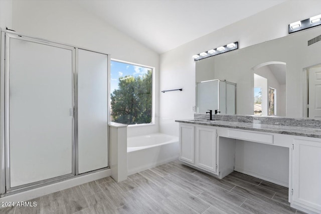 bathroom featuring hardwood / wood-style flooring, vanity, lofted ceiling, and plus walk in shower