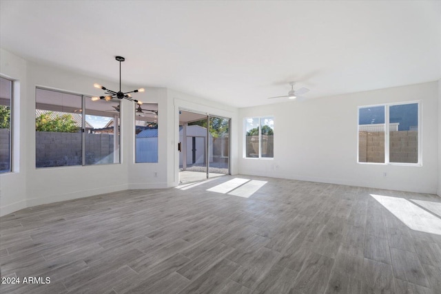 interior space with ceiling fan with notable chandelier and light wood-type flooring