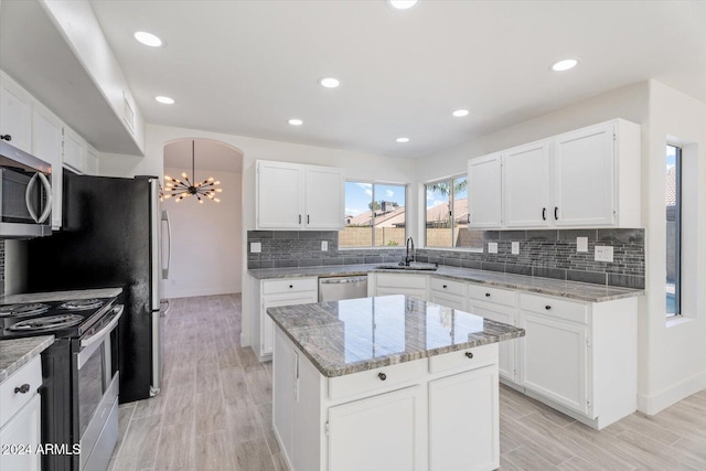 kitchen with white cabinetry, a kitchen island, light wood-type flooring, and appliances with stainless steel finishes