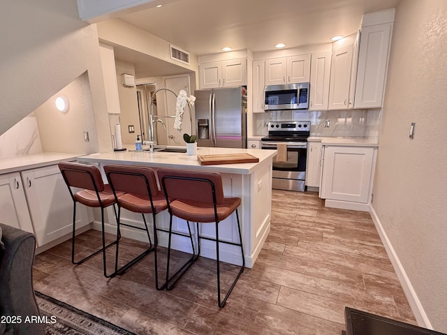 kitchen with stainless steel appliances, white cabinetry, and a breakfast bar area