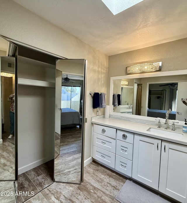 bathroom featuring vanity, hardwood / wood-style floors, and a skylight