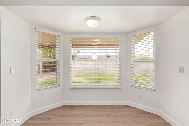 spare room featuring baseboards and wood finished floors