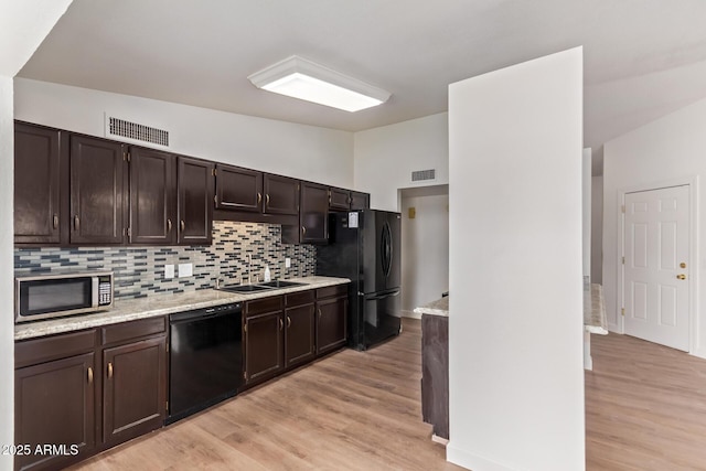 kitchen with tasteful backsplash, visible vents, light wood-type flooring, black appliances, and a sink