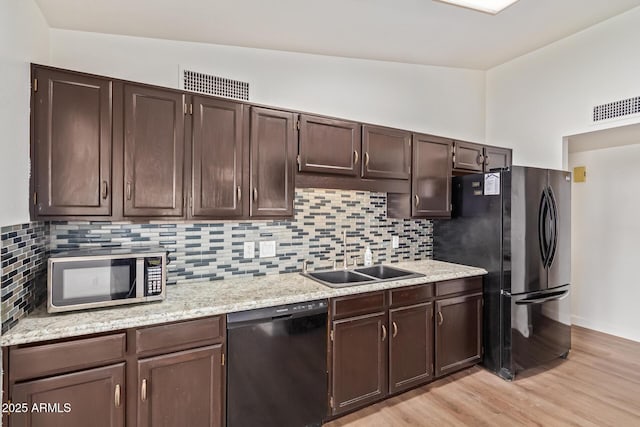 kitchen with visible vents, a sink, light wood-style flooring, and black appliances