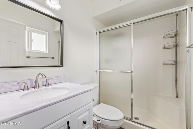 bathroom featuring a shower stall, toilet, and vanity