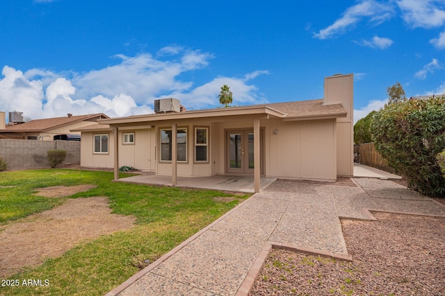 back of property with french doors, a yard, a patio, central air condition unit, and a fenced backyard