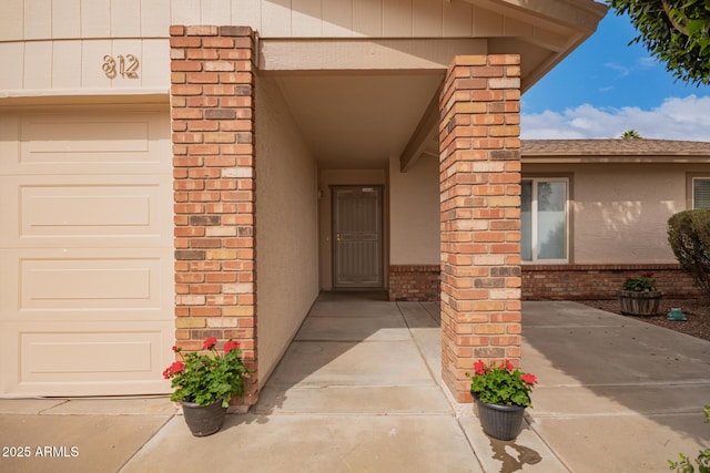 property entrance featuring a garage and brick siding