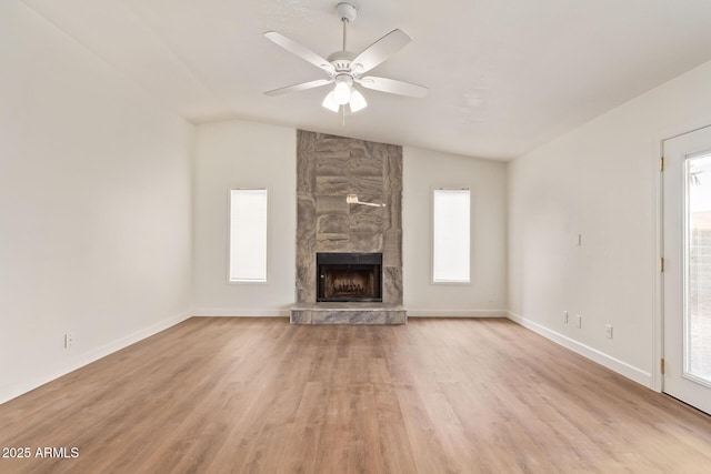 unfurnished living room featuring light wood-style flooring, a fireplace, vaulted ceiling, and a ceiling fan