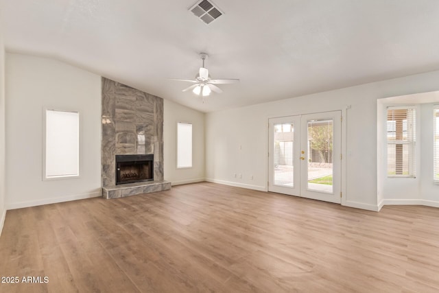 unfurnished living room featuring light wood-style floors, a fireplace, vaulted ceiling, and visible vents