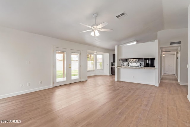 unfurnished living room featuring visible vents, a ceiling fan, vaulted ceiling, french doors, and light wood-type flooring