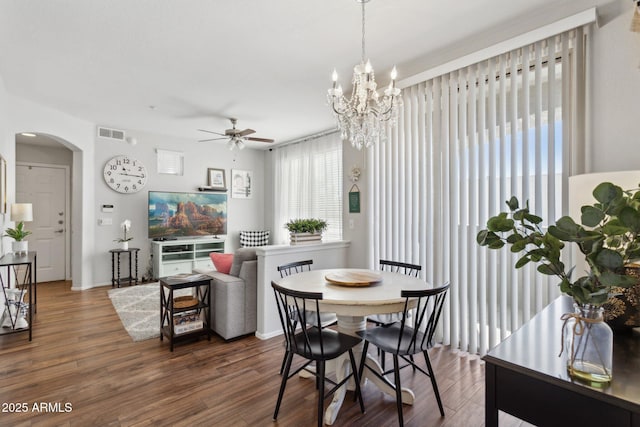 dining space with visible vents, a ceiling fan, dark wood-style floors, arched walkways, and baseboards