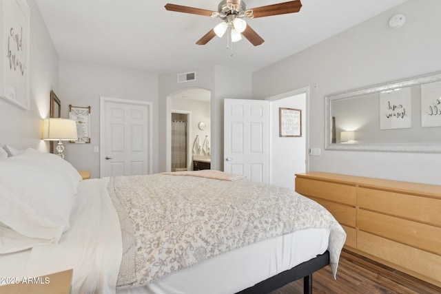 bedroom with visible vents, arched walkways, dark wood-type flooring, and a ceiling fan