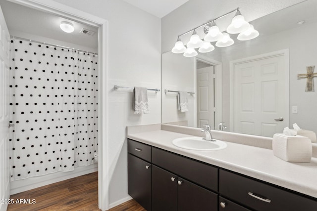 bathroom featuring visible vents, a shower with curtain, toilet, wood finished floors, and vanity