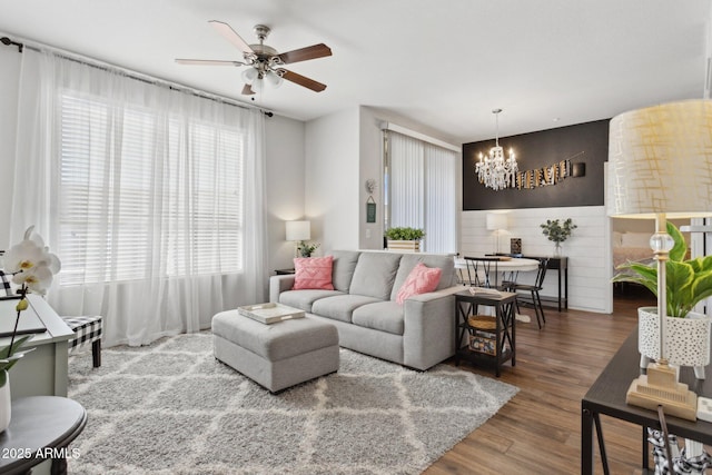 living room with ceiling fan with notable chandelier and wood finished floors