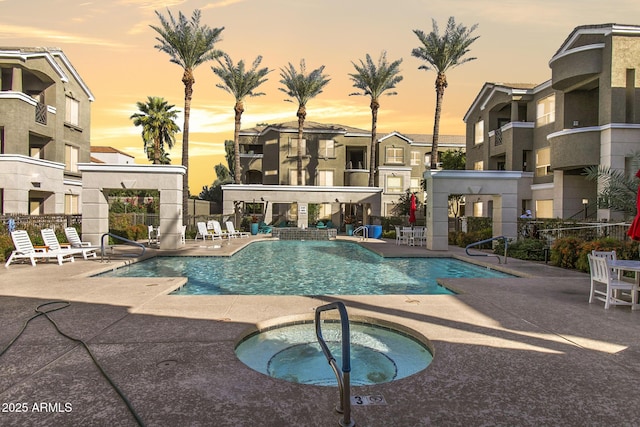 community pool featuring a community hot tub, a patio area, and fence