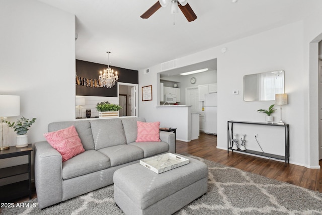 living room with visible vents, ceiling fan with notable chandelier, and wood finished floors