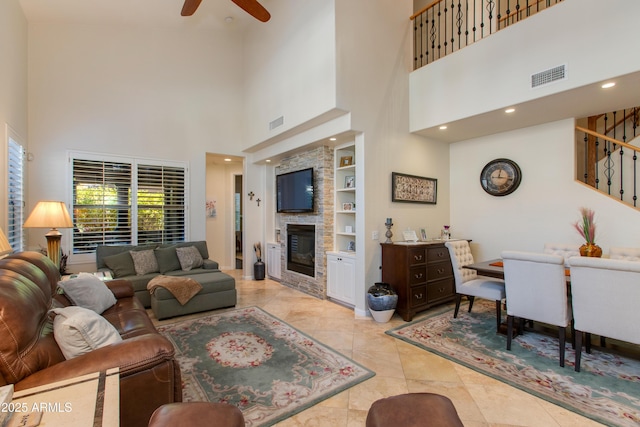 tiled living room featuring built in shelves, a large fireplace, and ceiling fan