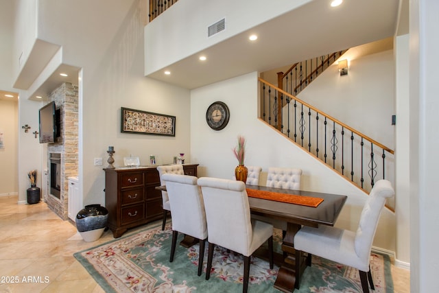 tiled dining area featuring a high ceiling and a stone fireplace