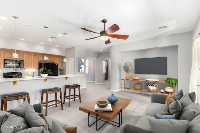 living room with ceiling fan, sink, and light carpet