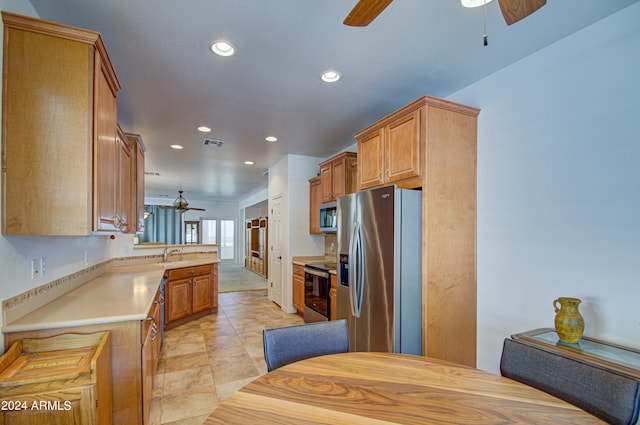 kitchen with ceiling fan, sink, appliances with stainless steel finishes, and kitchen peninsula