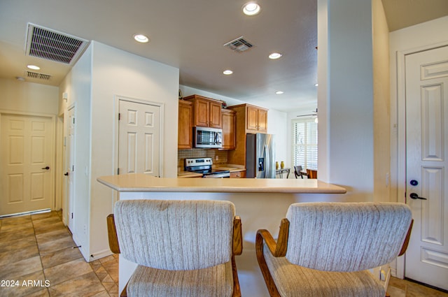 kitchen with light tile patterned floors, appliances with stainless steel finishes, kitchen peninsula, ceiling fan, and decorative backsplash