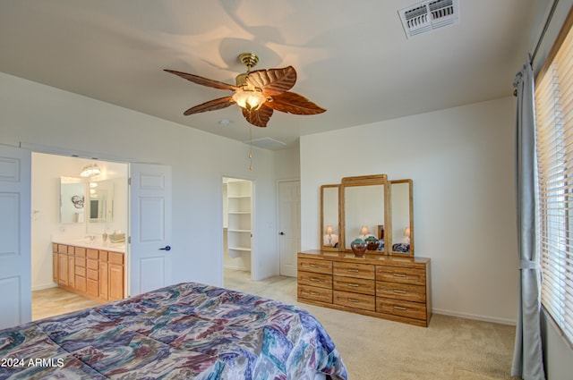 bedroom featuring multiple windows, ceiling fan, light carpet, and ensuite bath