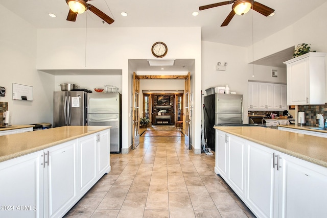 kitchen with white cabinets, stainless steel refrigerator, ceiling fan, and decorative backsplash