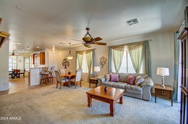 living room with a textured ceiling, a healthy amount of sunlight, ceiling fan, and light colored carpet