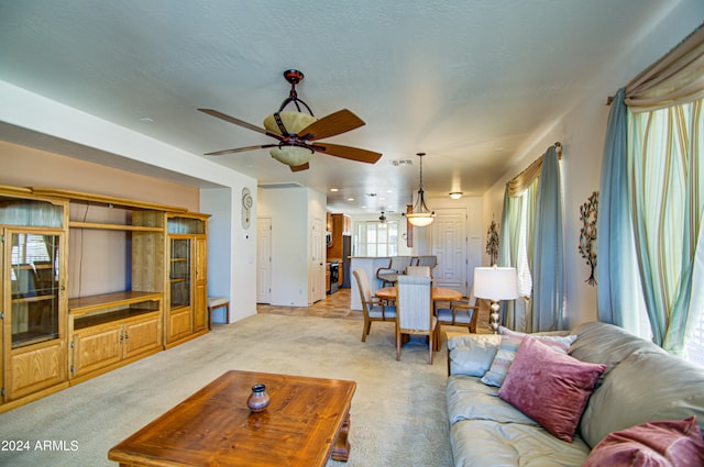 living room with ceiling fan, light carpet, and a textured ceiling