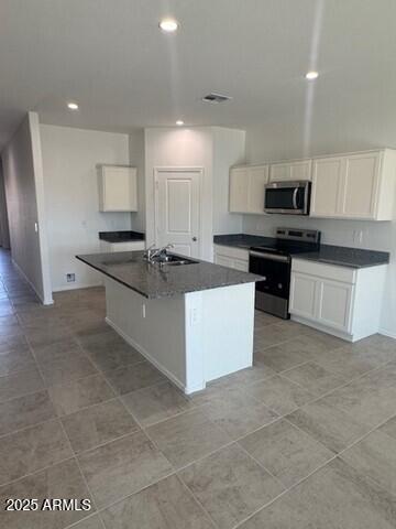 1336 W Hess Ave, Coolidge, AZ 85128 - kitchen featuring stainless steel appliances, dark countertops, white cabinets, a sink, and a center island with sink