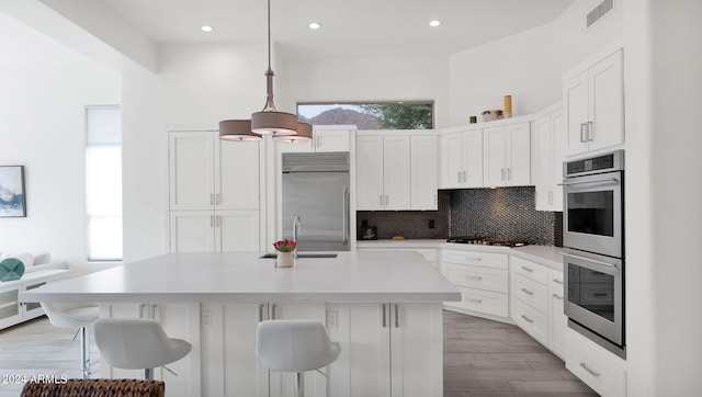 kitchen featuring pendant lighting, stainless steel appliances, backsplash, and a breakfast bar area