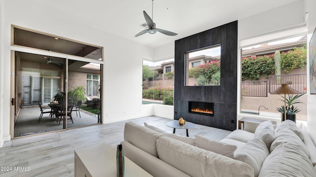 living area featuring baseboards, wood finished floors, a ceiling fan, and a tile fireplace