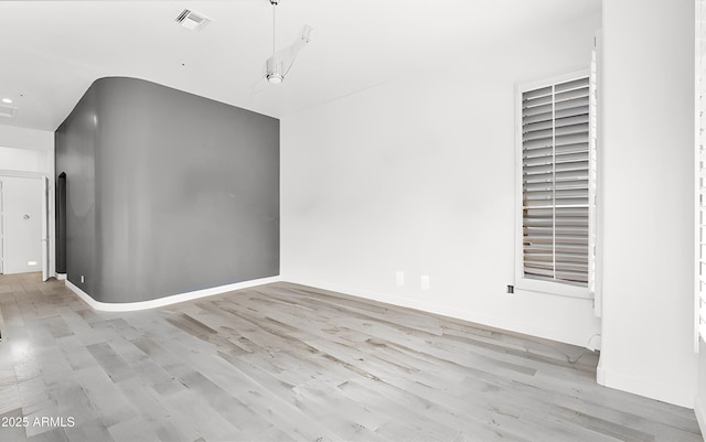 spare room with visible vents, baseboards, and light wood finished floors