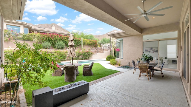 view of patio featuring a mountain view, a ceiling fan, and an outdoor pool