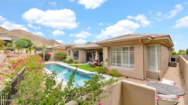 back of property with a fenced in pool, a fenced backyard, a mountain view, and stucco siding