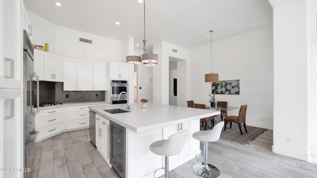 kitchen featuring visible vents, beverage cooler, decorative backsplash, light wood-style floors, and stainless steel appliances