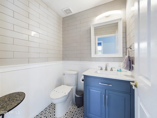 half bathroom with toilet, vanity, and visible vents