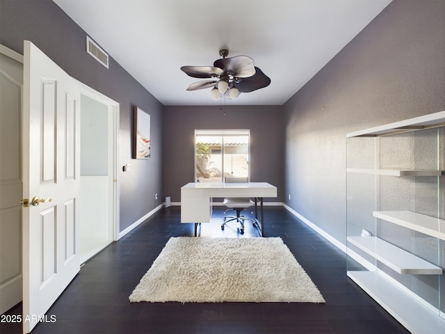 office featuring dark wood-type flooring, visible vents, ceiling fan, and baseboards