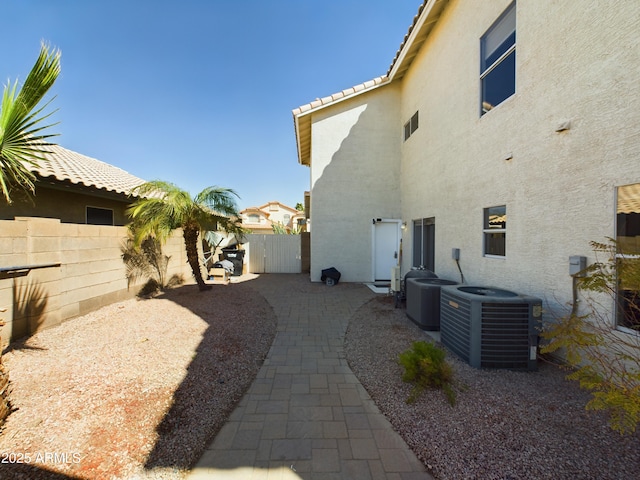 view of side of home with a fenced backyard, cooling unit, and stucco siding