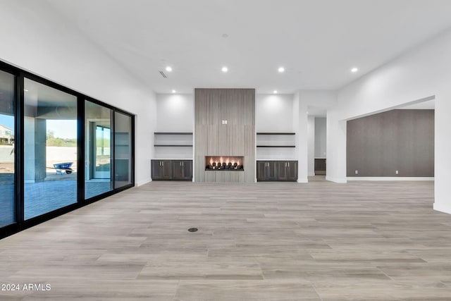 unfurnished living room featuring a large fireplace and light hardwood / wood-style floors