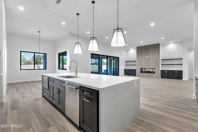 kitchen featuring pendant lighting, sink, light hardwood / wood-style flooring, stainless steel appliances, and an island with sink