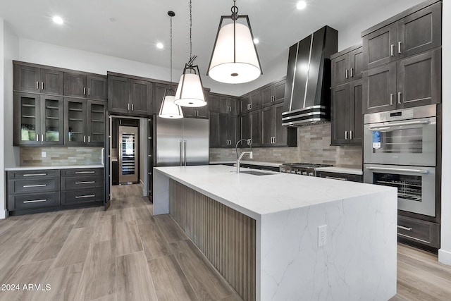 kitchen with pendant lighting, sink, stainless steel double oven, a large island, and wall chimney range hood