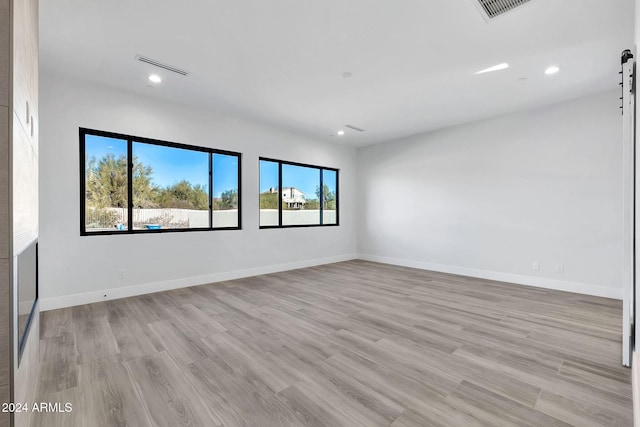 spare room with a barn door and light wood-type flooring