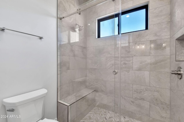 bathroom featuring toilet and a shower with shower door