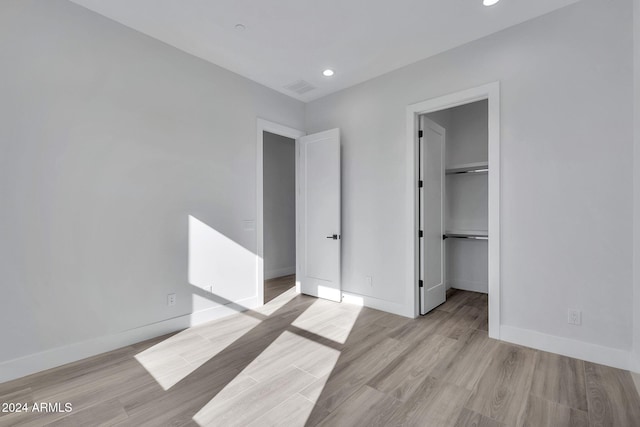 unfurnished bedroom featuring a walk in closet and light wood-type flooring