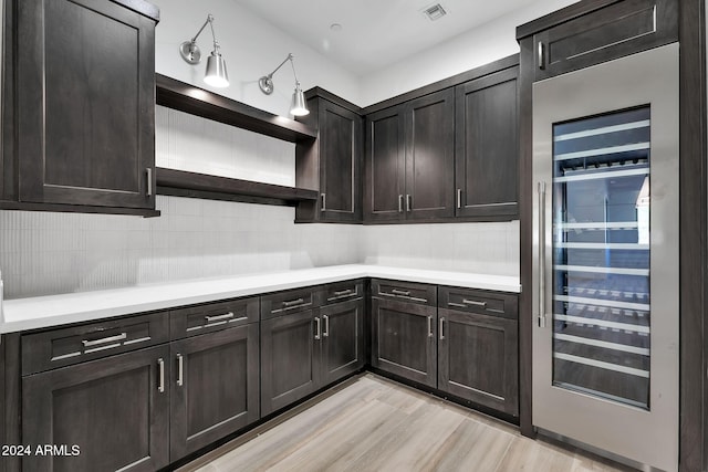 kitchen with backsplash, dark brown cabinets, and beverage cooler