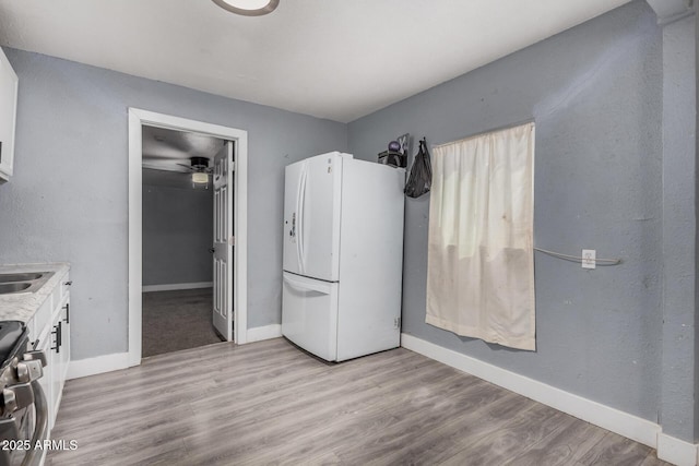 3913 W Sherman St, Phoenix, AZ 85009 - kitchen featuring freestanding refrigerator, stainless steel range, baseboards, white cabinetry, and light countertops
